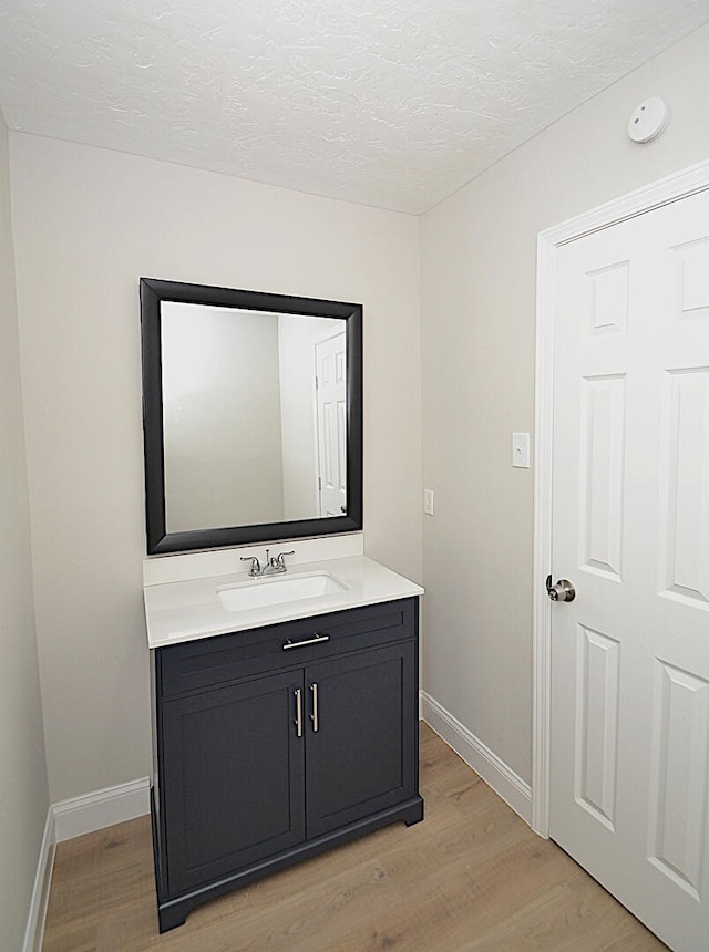 bathroom with wood-type flooring, vanity, and a textured ceiling