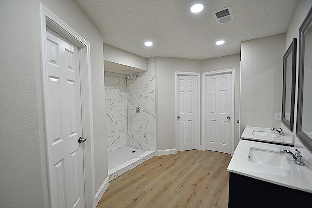 bathroom with vanity, hardwood / wood-style flooring, and tiled shower