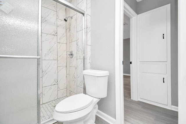 bathroom with hardwood / wood-style floors, a shower with shower door, and toilet