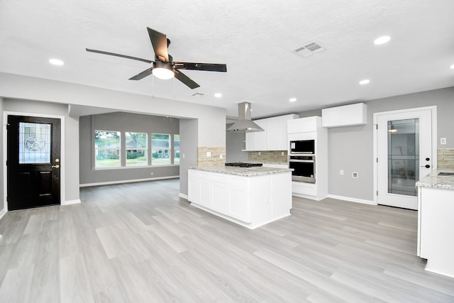 kitchen with tasteful backsplash, white cabinets, wall chimney exhaust hood, built in microwave, and gas stovetop