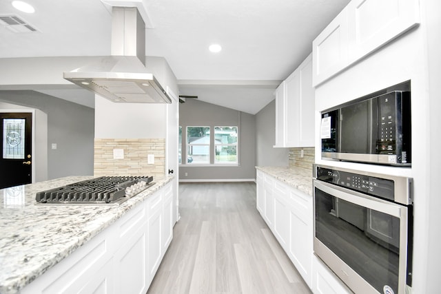 kitchen featuring backsplash, wall chimney range hood, white cabinetry, stainless steel appliances, and light stone countertops