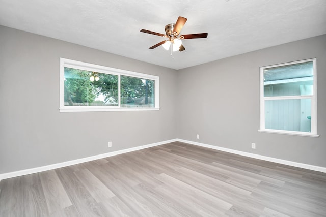 empty room featuring light hardwood / wood-style flooring, ceiling fan, and a textured ceiling