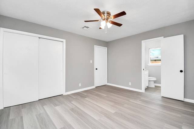 unfurnished bedroom featuring light wood-type flooring, ensuite bath, ceiling fan, and a closet