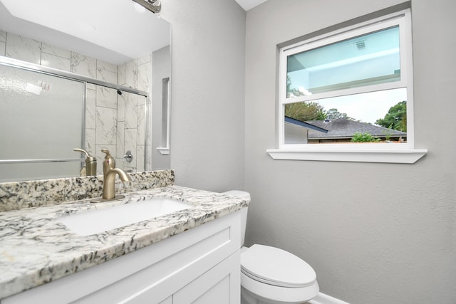 bathroom featuring vanity, toilet, and a shower with shower door