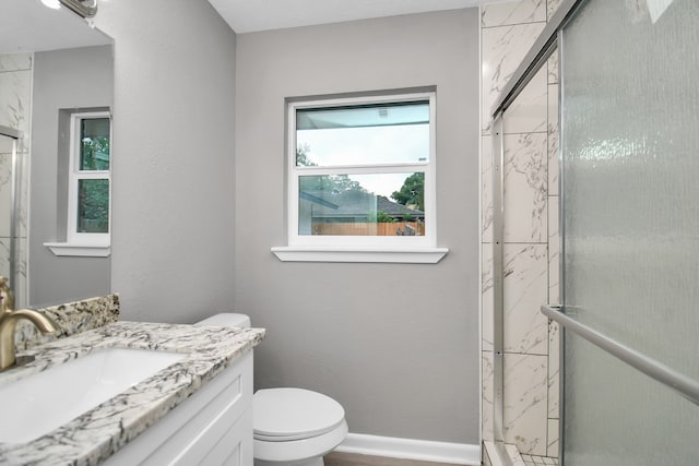 bathroom with a shower with shower door, vanity, and toilet