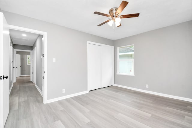 unfurnished bedroom with light wood-type flooring, ceiling fan, and a closet