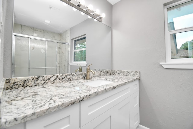 bathroom with a shower with door and vanity