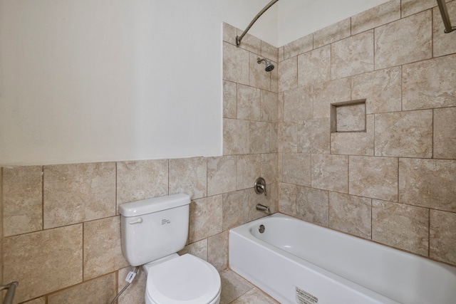 bathroom with tile walls, toilet, and tiled shower / bath