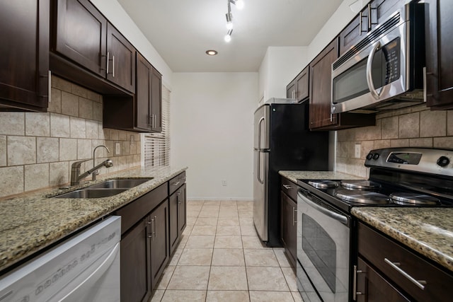 kitchen with light stone counters, tasteful backsplash, light tile patterned floors, stainless steel appliances, and sink