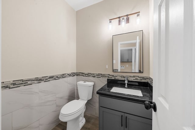 bathroom with vanity, tile walls, and toilet