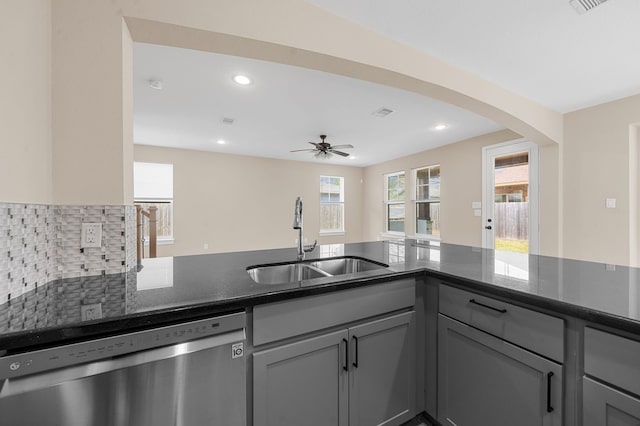 kitchen with sink, gray cabinetry, dishwasher, dark stone counters, and decorative backsplash