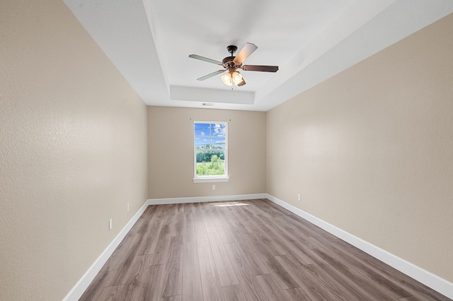 unfurnished room featuring light wood-type flooring, a raised ceiling, and ceiling fan