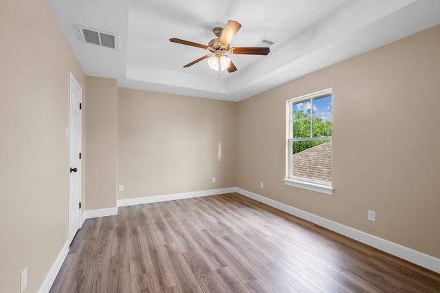 spare room featuring light hardwood / wood-style floors, a tray ceiling, and ceiling fan