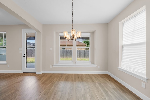 unfurnished dining area featuring a notable chandelier and light wood-type flooring