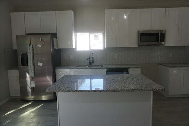 kitchen with white cabinetry, appliances with stainless steel finishes, dark hardwood / wood-style floors, light stone countertops, and sink