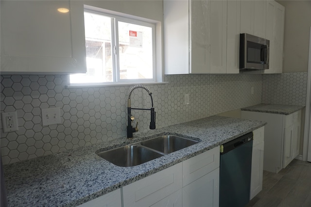 kitchen featuring black dishwasher, decorative backsplash, white cabinets, and sink