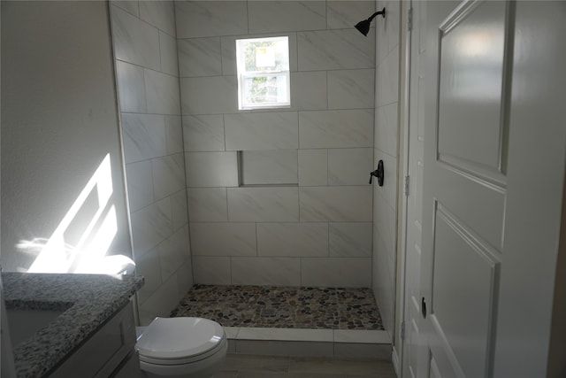 bathroom featuring toilet, vanity, and a tile shower