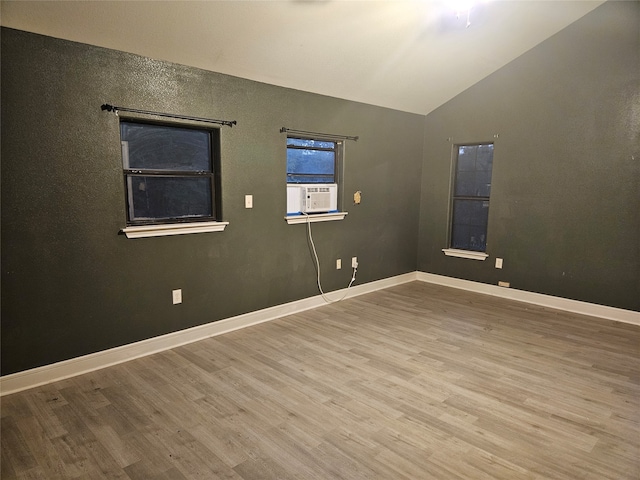 spare room featuring cooling unit, vaulted ceiling, and light hardwood / wood-style flooring