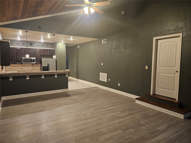 kitchen with dark brown cabinets, light wood-type flooring, a kitchen breakfast bar, and fridge with ice dispenser