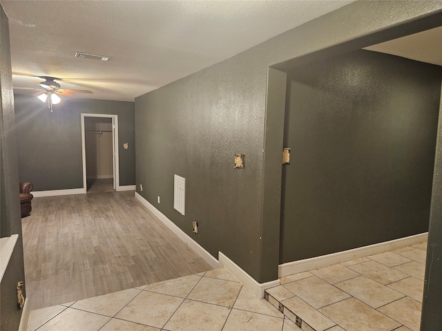 corridor with light hardwood / wood-style floors and a textured ceiling