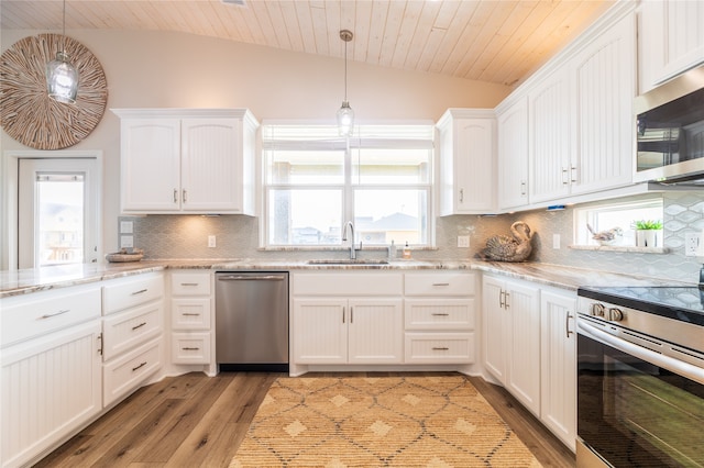 kitchen featuring white cabinets, sink, decorative light fixtures, stainless steel appliances, and vaulted ceiling