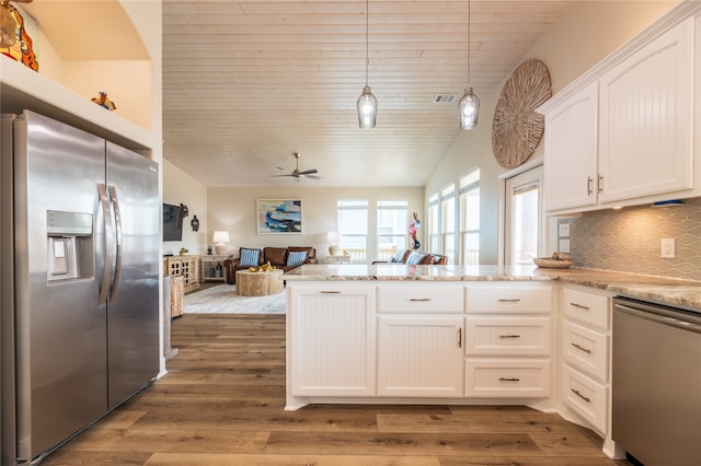 kitchen with light stone counters, decorative light fixtures, white cabinetry, appliances with stainless steel finishes, and dark hardwood / wood-style floors