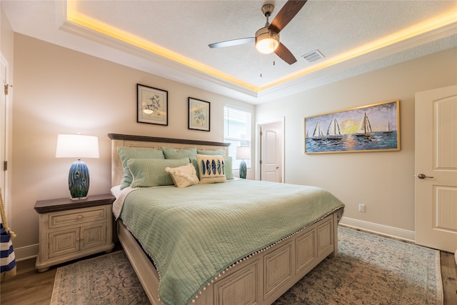 bedroom featuring a textured ceiling, a tray ceiling, ceiling fan, and light hardwood / wood-style flooring