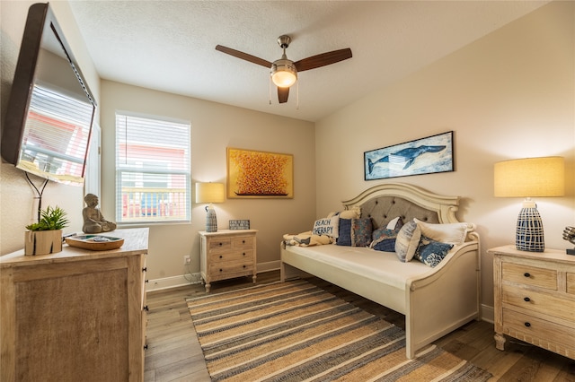 bedroom with ceiling fan, a textured ceiling, and dark hardwood / wood-style floors