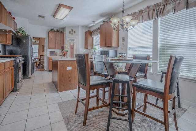 kitchen featuring light tile patterned flooring, ventilation hood, hanging light fixtures, an inviting chandelier, and appliances with stainless steel finishes