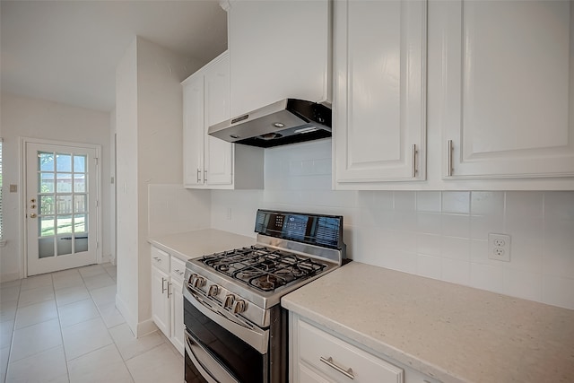 kitchen featuring extractor fan, backsplash, light tile patterned floors, stainless steel gas range oven, and white cabinets