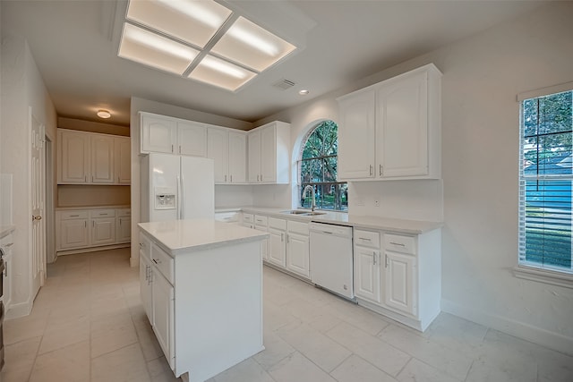 kitchen with white appliances, white cabinetry, a center island, and sink