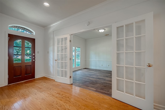 foyer entrance with french doors, crown molding, wood-type flooring, and a wealth of natural light