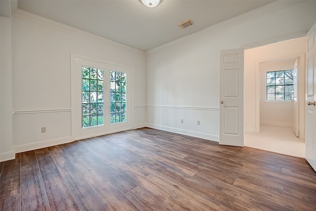 spare room featuring ornamental molding, plenty of natural light, and hardwood / wood-style floors