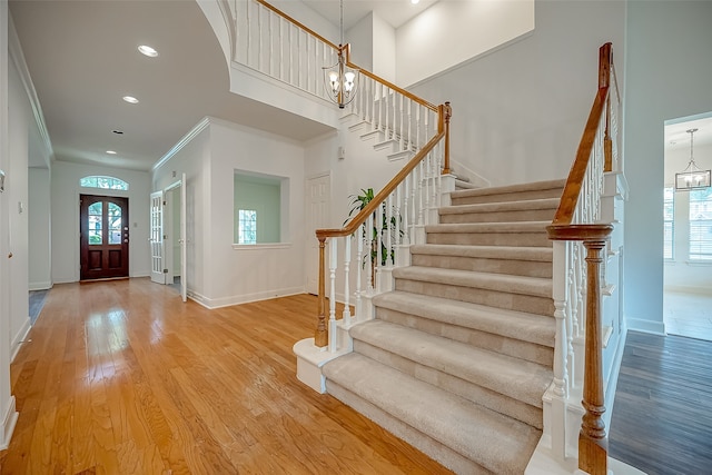 foyer featuring crown molding, hardwood / wood-style flooring, an inviting chandelier, and a high ceiling