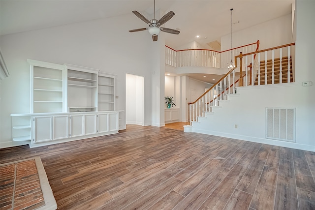 unfurnished living room featuring hardwood / wood-style flooring, high vaulted ceiling, built in features, and ceiling fan