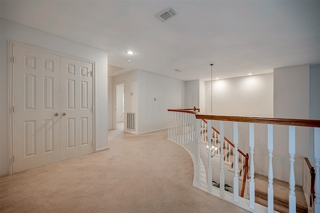 hall featuring light carpet and a chandelier