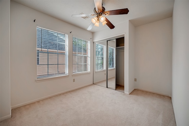 unfurnished bedroom with light colored carpet, a closet, and ceiling fan