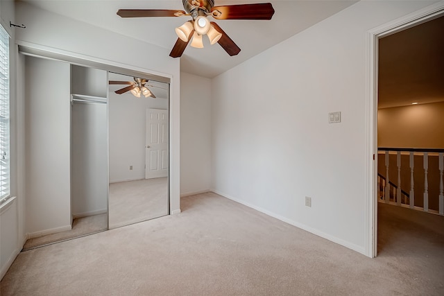 unfurnished bedroom with a closet, light colored carpet, and ceiling fan