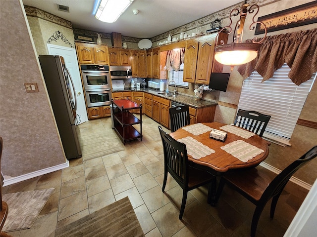 kitchen with dark stone countertops, appliances with stainless steel finishes, and sink