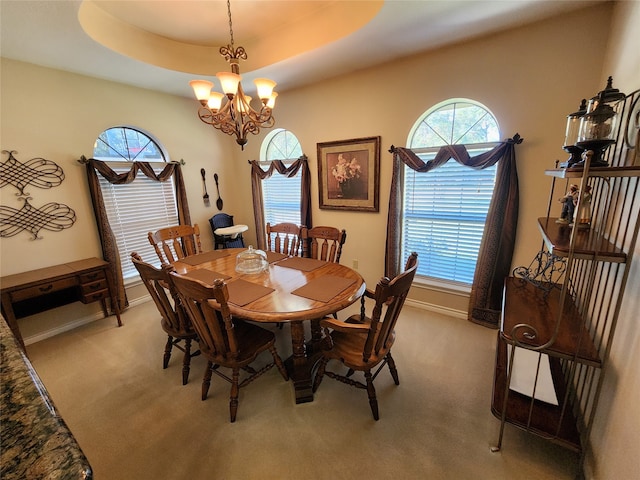 dining space featuring carpet, a tray ceiling, a chandelier, and a wealth of natural light