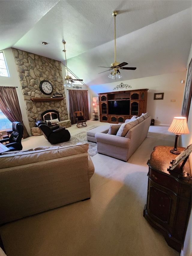 carpeted living room with ceiling fan, a stone fireplace, and vaulted ceiling