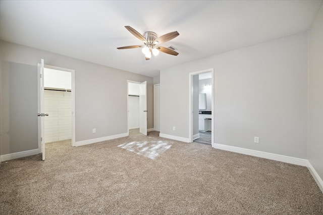 unfurnished bedroom with ensuite bath, carpet, and ceiling fan