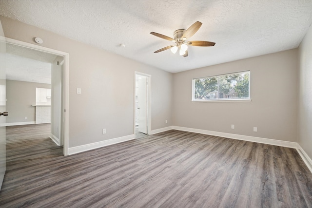 empty room featuring ceiling fan, a textured ceiling, and dark hardwood / wood-style flooring