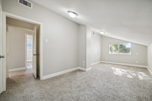 bonus room with a textured ceiling, vaulted ceiling, and light colored carpet