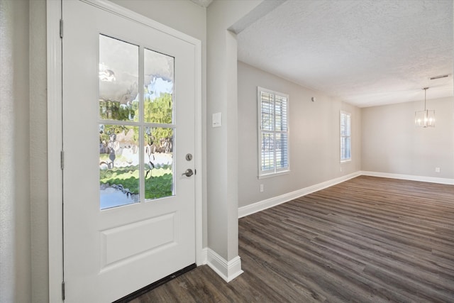 doorway featuring a notable chandelier, a textured ceiling, and dark hardwood / wood-style flooring