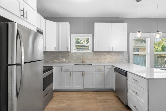 kitchen with stainless steel appliances, kitchen peninsula, white cabinets, and sink