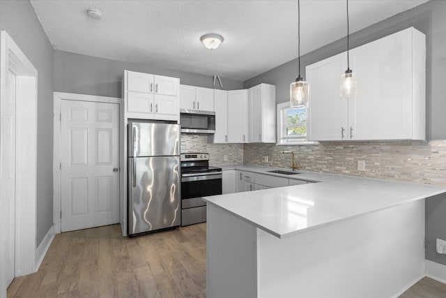 kitchen with pendant lighting, sink, kitchen peninsula, white cabinetry, and stainless steel appliances