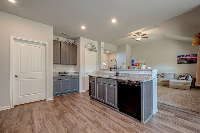 kitchen featuring an island with sink, light stone counters, sink, light hardwood / wood-style floors, and dishwasher