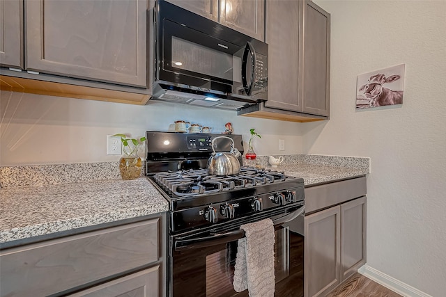 17624 Cedar Crest Dr, Conroe, TX 77306 - kitchen featuring black appliances, light stone counters, and wood finished floors