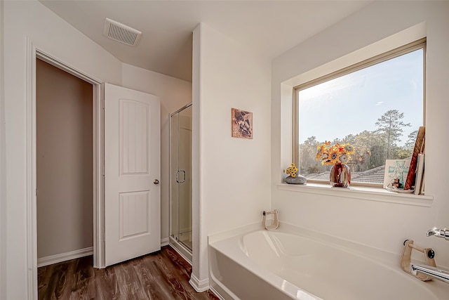 bathroom featuring wood-type flooring and shower with separate bathtub